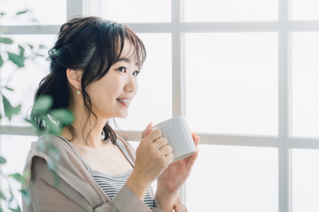 朝に飲み物を飲んでリラックスする女性